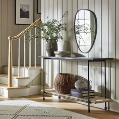 an entryway with a mirror, vases and baskets on the shelf next to it