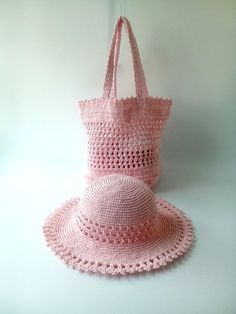 a pink crocheted hat and bag sitting on top of a white table next to each other