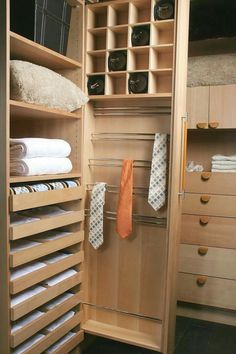 an organized closet with folded towels and ties hanging on the clothes rack, in front of wooden cabinets