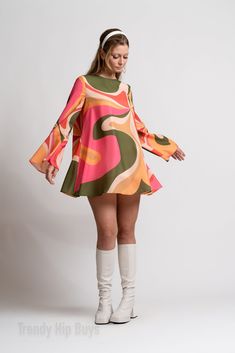 Step into the enchanting world of 70s Dress Style with our Bell Sleeve Dress, a captivating piece that encapsulates the spirit of the groovy era. This 60s 70s mini dress is a Boho Dress with a distinctive Bohemian touch, perfect for those seeking a Hippie Dress that exudes both charm and style. The Multicolor Tent Dress features a groovy pattern print inspired by the psychedelic aesthetics of the 70s, creating a visually striking and unique look. This slip-on dress is designed for ease and comfort, complemented by bell sleeves that add a touch of vintage flair. The single button enclosure behind the neckline enhances the Bohemian feel of the dress. Crafted from chiffon and fully lined material, this Groovy 70s Style Dress ensures a luxurious feel and graceful movement. The 100% polyester c Rich 60s Fashion, 60s Street Fashion, 1970s Formal Fashion, Groovy Glam Outfit, 70s Flare Sleeve Dress, Bell Sleeve Dress 70s, Vintage Orange Dress, Womens 1970s Fashion, Retro A-line Dress With Vintage Print