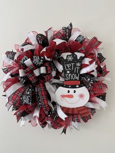 a red and white wreath with a snowman on it's side, hanging from the wall