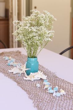 baby's breath in a vase on a table with sea shells and starfish