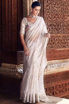 Experience the seamless blend of tradition and modernity with our exquisite royal nandi tissue sari in ivory. This exceptional piece is adorned with multicolor aari work, gota work, and meticulously-done hand embroidery, showcasing the rich heritage of indian craftsmanship. The intricate patterns lining the delicate tissue fabric, combined with an unconventional tasseled pallu, create an unforgettable sari that epitomizes the strength and grace of the Indian woman.