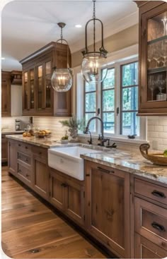 a kitchen filled with lots of wooden cabinets and counter top space next to a window