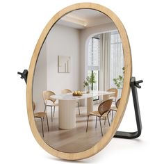 a round mirror sitting on top of a wooden table next to a white dining room table