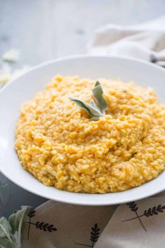 a white bowl filled with yellow rice on top of a cloth covered table next to a napkin