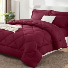 a bed with red comforter and pillows in a room