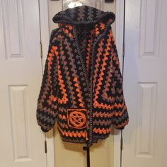 an orange and black crocheted jacket hanging on a door