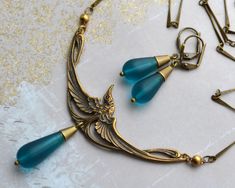 "VINTAGE ELEMENTS Unique Jewellery, Handmade from Vintage Inspired Deigns Art Nouveau style antiqued Gold Brass Necklace & Earring set, with a stunning Great Blue Heron Centrepeice and striking Teal Blue Frosted Sea Glass Teardrops. The Necklace has an elegant antiqued brass bar chain and measures 17 1/4\" (44cm) from end to end  plus a 2 1/2\" (6cm) extender chain. The matching Earrings have antiqued brass leverback earwires  and measure 4cm from the top of the earwires. Necklace and Earrings c Vintage Brass Jewelry With Turquoise, Vintage Turquoise Brass Jewelry, Antique Blue Brass Jewelry, Bronze Art Nouveau Jewelry With Antique Finish, Art Deco Jewelry With Antique Finish As Gift, Blue Antique Finish Jewelry For Gift, Blue Antique Finish Jewelry Gift, Handmade Vintage Jewelry Sets As Gift, Art Deco Antique Finish Jewelry Gift