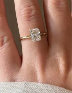 a woman's hand with a diamond ring on top of her finger and an engagement band