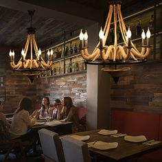 people sitting at a table in a restaurant with plates on the table and lights hanging from the ceiling