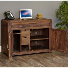 a wooden desk with drawers and a laptop on it's top shelf next to a potted plant