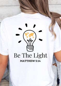 **DESCRIPTION** Illuminate your faith with this inspiring "Be the Light" t-shirt, featuring a vibrant graphic of a light bulb filled with a yellow map of the Earth. Inspired by Matthew 5:14, this design serves as a powerful reminder that we are called to shine our light in the world, spreading hope and love to all corners of the Earth. Perfect for everyday wear, this shirt is a stylish way to share your faith and encourage others to reflect Christ's light in their lives. **SHIRT DETAILS** Comfor Faith Shirts, Matthew 5, Bible Verse Shirt, Be The Light, Jesus Shirt, Faith Shirt, Christian Shirt, Jesus Shirts, Shirts For Women