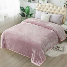 a pink bed with white pillows and blankets