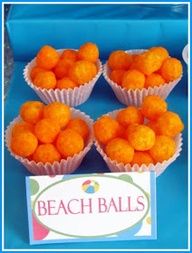 small orange balls are sitting on a blue tablecloth next to a sign that says beach balls