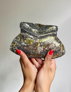 A stylish 1930s clutch purse.  Entirely embellished with tiny glass beads and sequins in tones of gold and silver. Some of the sequins have tarnished to a pale metallic pink.  There is a handle loop at the back.  Fastens with a press stud.  Lined with rayon. There is a handy little side pocket. Highly usable with due care.  Measurements: This purse does not fit a mobile phone.  The top- 12cm across Down- 12 cm The bottom- 19 cm across. Condition: Minimal missing embellishments. The sequins have tarnished and aged in areas throughout. Inside, there is a large watery mark and some general darkening.  Please ask if you have any questions. x Vintage Wedding Accessories, Sparkly Clutch, Deco Vintage, Metallic Pink, Sequin Beading, Gold Glass, Side Pocket, Clutch Purse, Clutch Handbag