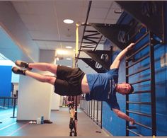 a man doing a handstand on top of a ladder in an indoor gym