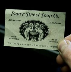 a person holding up a paper street soap co business card