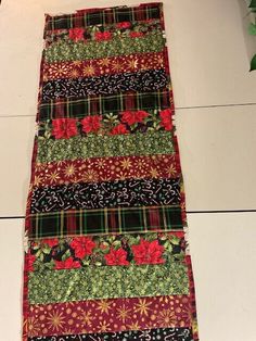 a table runner made out of fabric with flowers and leaves on the bottom, sitting on top of a white tile floor