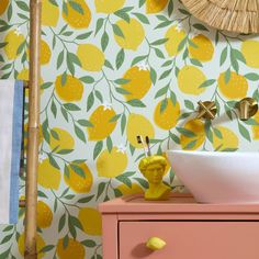 a bathroom with yellow lemons on the wall and a white sink in front of it