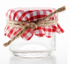 a glass jar filled with red and white gingham fabric wrapped around twine