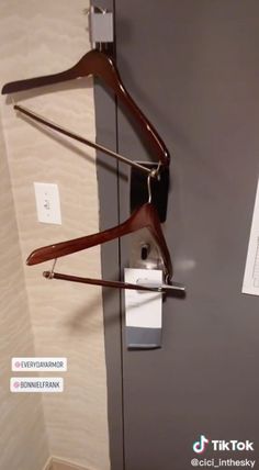 a pair of wooden clothes hangers hanging on the wall next to a toilet paper dispenser