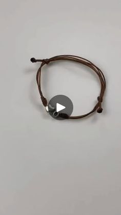 a brown cord bracelet with a silver disc on it and a black bead around the clasp