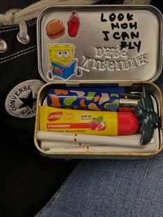 an open tin with some writing on it and various items in the bottom half of it