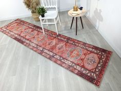 a large red rug on the floor next to a white chair and potted plant