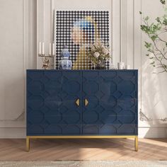 a blue and gold cabinet in a white room with plants on the sideboard next to it