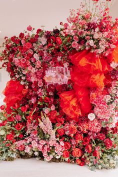 an arrangement of red flowers and greenery on display