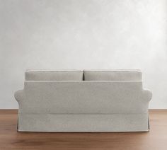 a couch sitting on top of a wooden floor next to a white wall in an empty room