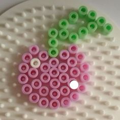 a close up of a plastic object on a white surface with green and pink circles