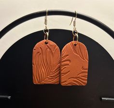 two brown tags hanging from hooks on a black stand