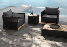 an outdoor seating area with two chairs and a coffee table next to a swimming pool