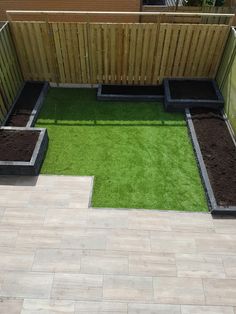 a small backyard with grass and wooden fenced in area on the other side is a raised garden bed