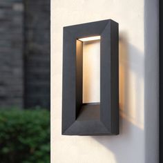 a wall mounted light on the side of a building with trees in the back ground