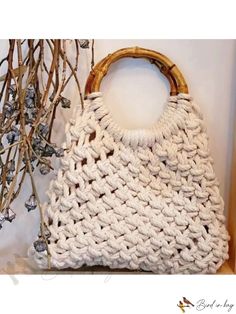 a white crocheted handbag sitting on top of a table next to branches