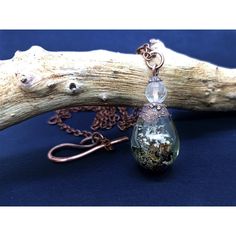 a piece of drift wood with a glass bead hanging from it's end