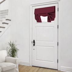 a living room with a white couch and a red window valance on the door