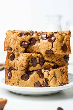 three chocolate chip cookies stacked on top of each other in front of a white plate