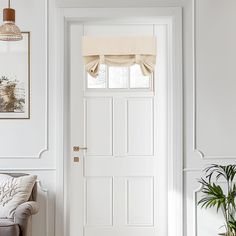 a living room with a white door and window coverings on the windowsill next to a couch