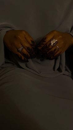 a woman's hands with gold rings on her fingers, wrapped in a blanket