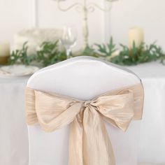 the back of a chair with a bow tie on it and candles in the background