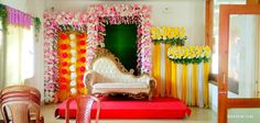 a decorated stage set up for a wedding ceremony with flowers and greenery on the walls