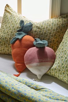 two decorative pillows sitting on top of a bed next to each other in front of a window