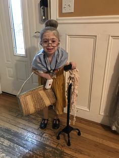 an old woman with glasses holding a cane and smiling at the camera while standing in front of a door