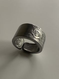 a silver ring with an intricate design on the outside and inside, sitting on a gray surface