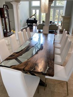 a dining room table with white chairs and a piano in the backgrounge