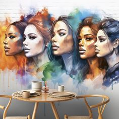 three women's faces painted on the wall next to a table with two cups